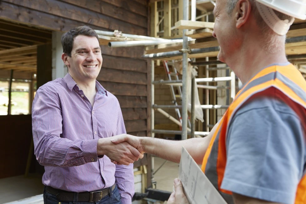 Builder and client shaking hand on construction site