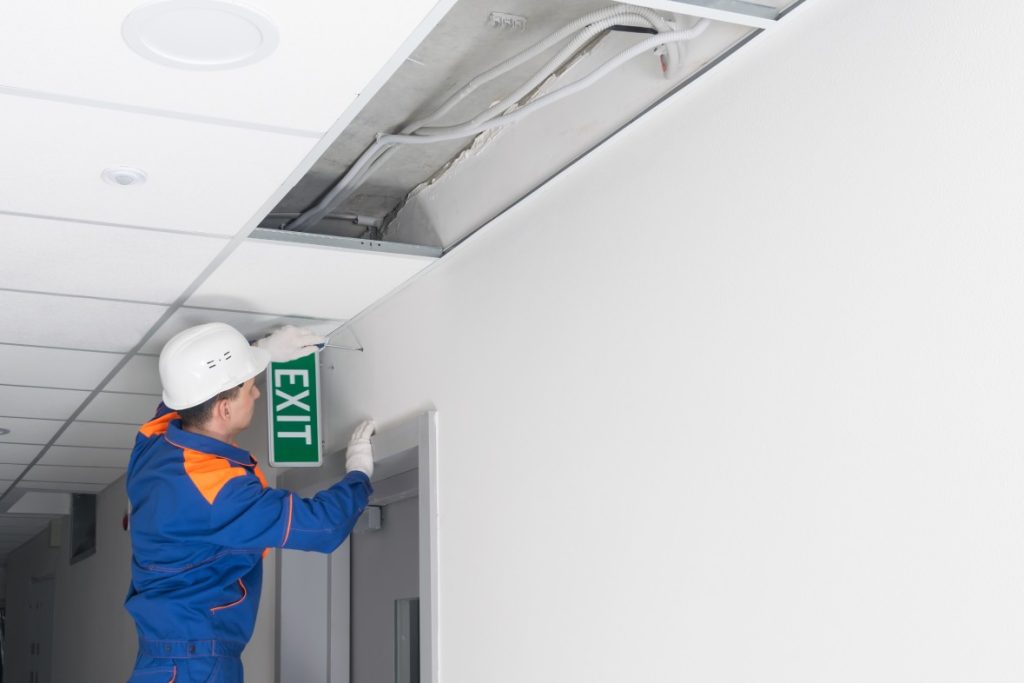 Repairman fixing exit sign in commercial building